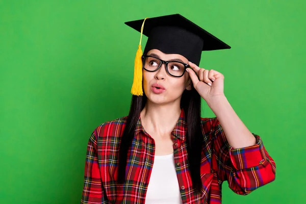 Portret van aantrekkelijk minded meisje dragen meesters cap aanraken specs kopiëren ruimte geïsoleerd over helder groene kleur achtergrond — Stockfoto