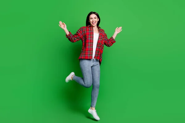 フルボディ写真のクレイジーブルネット毛深い若い女性ジャンプ着用赤いシャツジーンズ隔離された緑の色の背景 — ストック写真