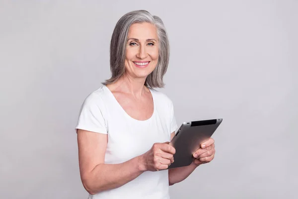 Photo de jolie optimiste ceo senior lady hold tablet porter t-shirt blanc isolé sur fond de couleur grise — Photo