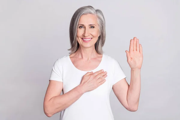 Photo of aged woman happy positive smile hold hand make promise oath swear tell truth isolated over grey color background