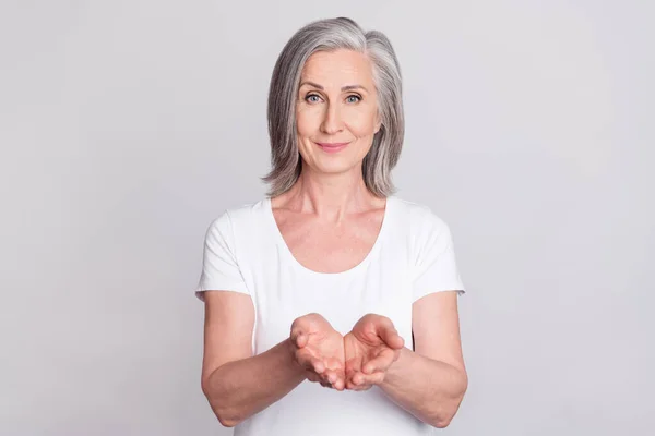 Foto da mulher idosa feliz sorriso positivo segurar as mãos produto anúncio dar tomar isolado sobre fundo de cor cinza — Fotografia de Stock