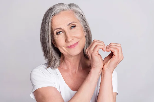 Foto da mulher sênior feliz sorriso positivo mostrar dedos coração figura romântica isolado sobre fundo de cor cinza — Fotografia de Stock