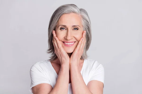 Foto de señora madura adorable brillante usar ropa blanca brazos mejillas sonriendo aislado fondo de color gris —  Fotos de Stock