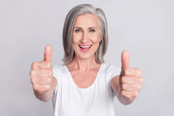 Foto de señora madura brillante lindo desgaste blanco que muestra dos pulgar hacia arriba sonriendo fondo de color gris aislado —  Fotos de Stock