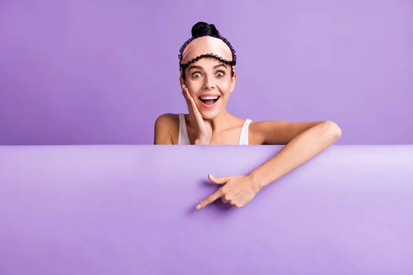 Foto portrét roztomilé dívky ukazující prstem prázdný prostor na plakátu dotýkající se tváře překvapen izolované na pastelové fialové barvy pozadí — Stock fotografie