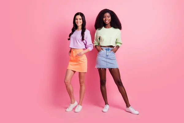 Full body photo of charming cute young women hold hands pockets good mood isolated on pastel pink color background — Stock Photo, Image