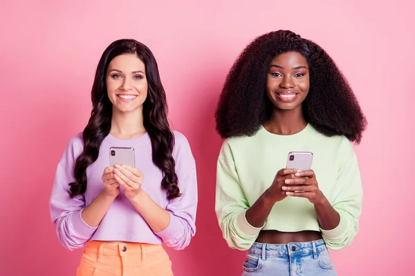 Retrato de chicas alegres atractivas utilizando dispositivo de navegación smm comentario aislado sobre fondo de color pastel rosa — Foto de Stock