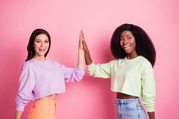Photo de deux dames excitées lever les mains applaudir cinq porter sweat-shirt recadré isolé fond de couleur jaune — Photo