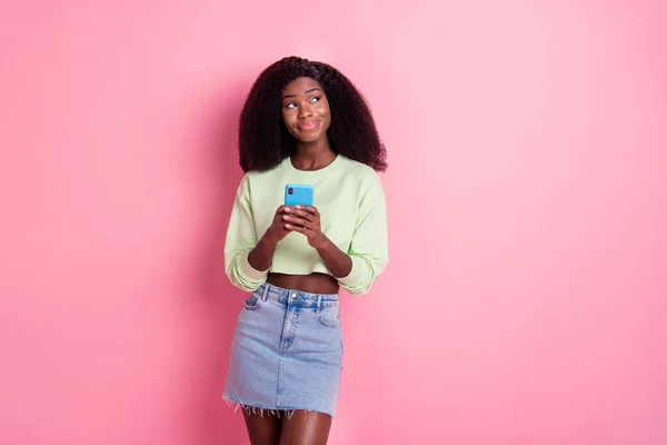 Zdjęcie marzycielski uroczy afro amerykańskiej pani wygląd pusty przestrzeń wyobrazić post hold telefon izolowany na różowy kolor tła — Zdjęcie stockowe