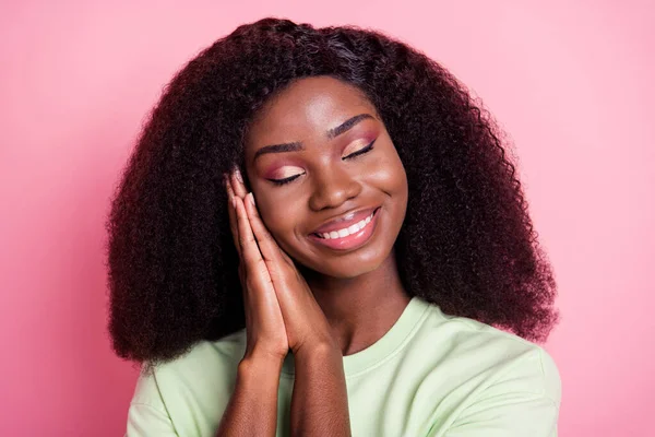 Φωτογραφία της ήρεμης χαρούμενη ευτυχισμένη γυναίκα σκούρο δέρμα κρατήστε τα χέρια πρόσωπο νυσταλέο χαμόγελο απομονώνονται σε παστέλ ροζ χρώμα φόντο — Φωτογραφία Αρχείου