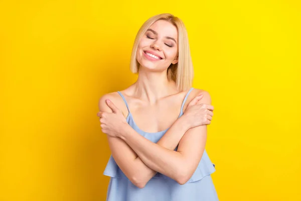 Foto de relaxar loira curto cabelo senhora abraçar-se usar top azul isolado no fundo de cor amarela — Fotografia de Stock