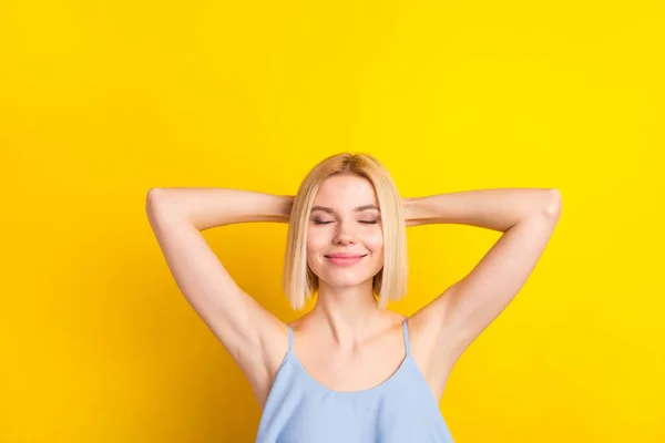 Foto de calma agradável loiro curto cabelo senhora mãos cabeça desgaste azul top isolado no fundo de cor amarelo vívido — Fotografia de Stock