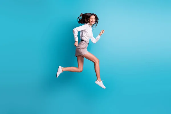 Full size profil zdjęcie śmieszne brunetka dziewczyna skok bieg nosić spódnica trampki izolowane na ciemnym tle — Zdjęcie stockowe
