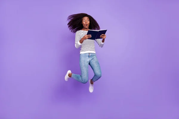 Longitud completa vista del tamaño del cuerpo de la atractiva chica alegre sorprendida saltando libro de lectura aislado sobre violeta color púrpura fondo —  Fotos de Stock
