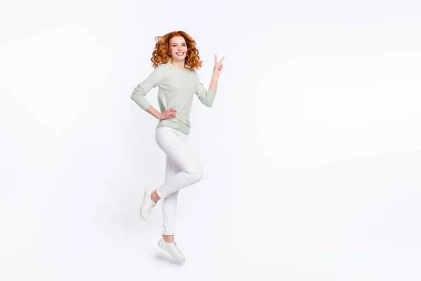 Longitud completa tamaño del cuerpo foto mujer joven pelo rojo saltando alto mostrando v-signo aislado color blanco fondo — Foto de Stock
