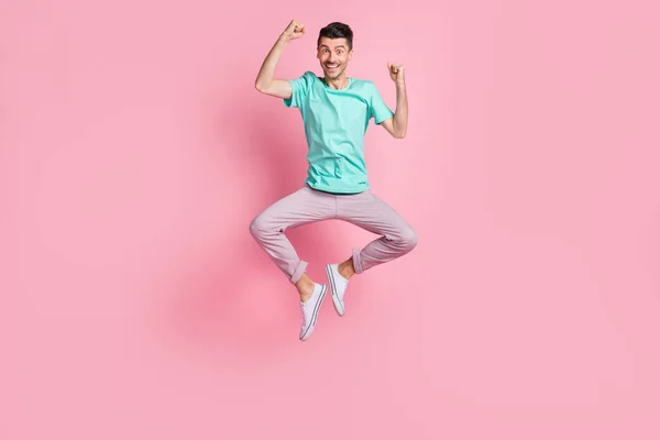 In voller Länge Foto von jungen aufgeregten Mann glücklich Lächeln feiern Sieg Fäuste springen isoliert über pastellfarbenen Hintergrund — Stockfoto