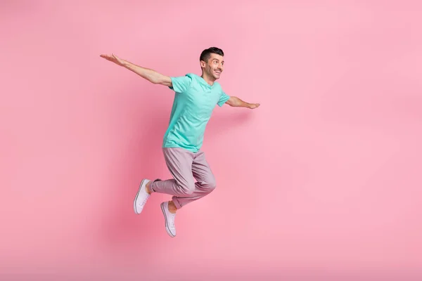Full storlek profil sida foto av ung man glad positiv leende hoppa upp händer vinge flyga isolerad över pastell färg bakgrund — Stockfoto