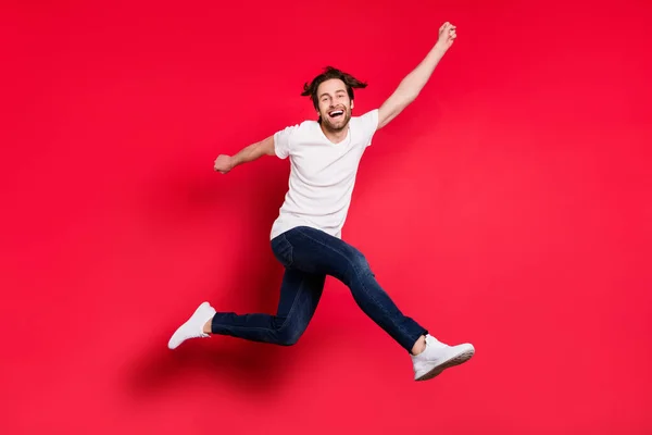Pełna długość profil boczny zdjęcie młodego faceta szczęśliwy pozytywny uśmiech radować zwycięstwo sukces iść spacer skok odizolowany na czerwonym tle kolor — Zdjęcie stockowe