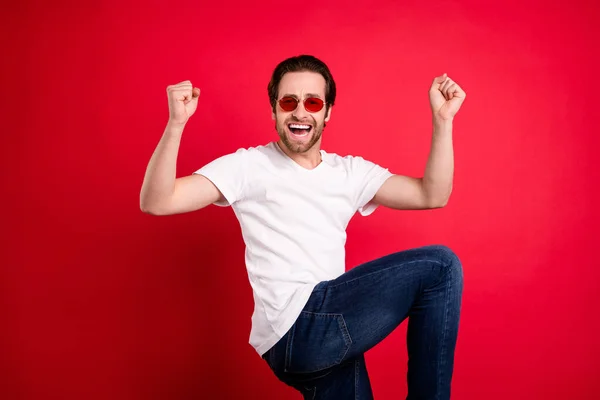 Foto av glada glada glad ung man höja knytnävarna bära cool funky solglas isolerad på röd färg bakgrund — Stockfoto