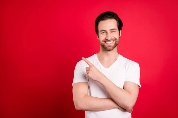 Photo de belle jeune homme brun coiffure croisée bras point vide espace porter blanc t-shirt isolé sur fond de couleur rouge — Photo