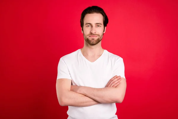 Foto de confianza joven marrón peinado hombre cruzó brazos usar camiseta blanca aislada en el fondo de color rojo — Foto de Stock