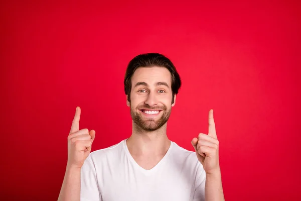 Foto von fröhlichen glücklichen jungen Mann zeigen Sie mit den Fingern nach oben leeren Raum gute Laune isoliert auf rotem Hintergrund — Stockfoto