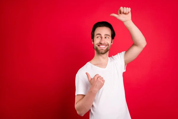 Foto de atraente jovem agradável homem feliz apontar dedos vazio espaço venda notícias isoladas no fundo de cor vermelha — Fotografia de Stock