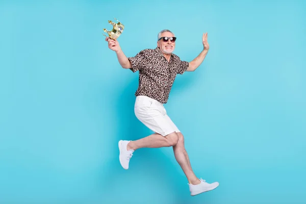 Volledige grootte foto van aantrekkelijke koele oude man spring omhoog lucht vasthouden hand kroon zomer geïsoleerd op blauwe kleur achtergrond — Stockfoto