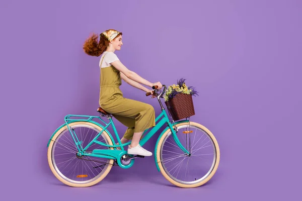 Perfil vista lateral retrato de atraente alegre menina equitação ciclo rápido ar soprando cabelo isolado sobre violeta cor roxa fundo — Fotografia de Stock