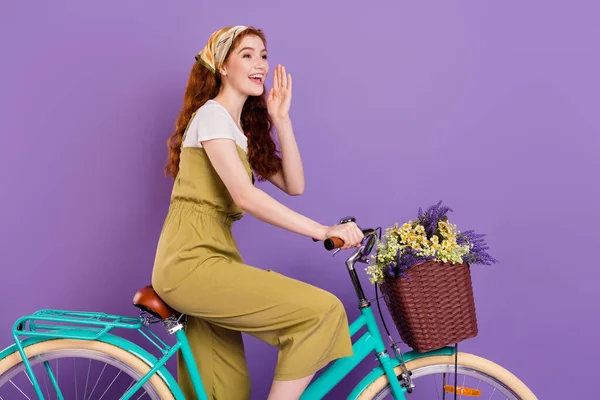 Profiel zijaanzicht portret van aantrekkelijke vrolijke meisje paardrijden cyclus bellen vriend geïsoleerd over violet paarse kleur achtergrond — Stockfoto