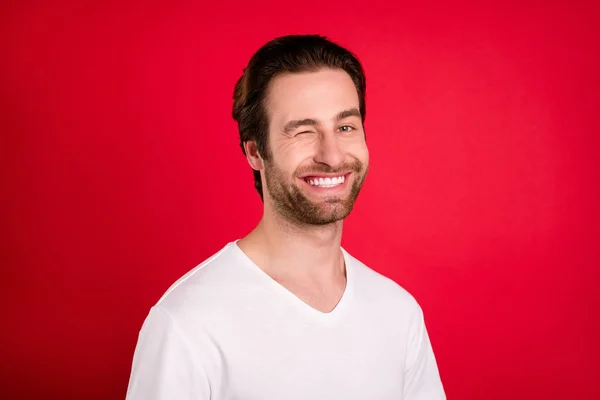Photo of cheerful positive happy charming man wink eye good mood smile isolated on red color background Royalty Free Stock Images