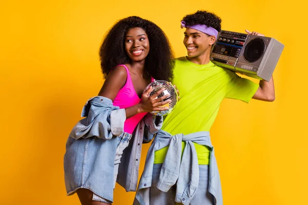 Porträt von attraktiven fröhlichen funky Paar umarmen Spaß Tragen Retro-Player isoliert über leuchtend gelben Farbhintergrund — Stockfoto