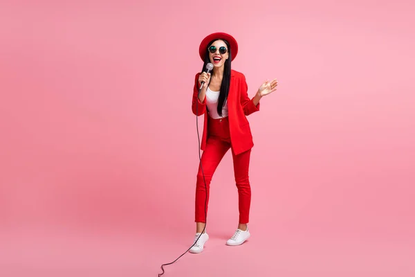 Ritratto fotografico a figura intera di ragazza carina che canta tenendo il microfono in una mano isolato su sfondo rosa pastello — Foto Stock