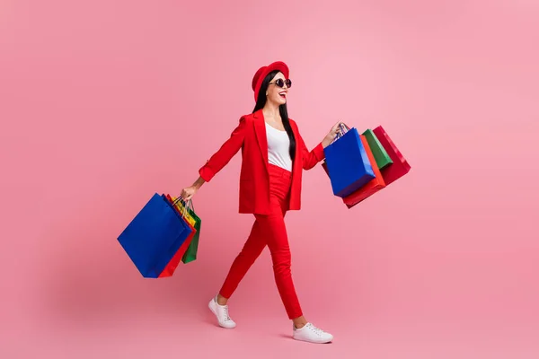 Foto retrato cuerpo completo vista lateral de la niña caminando con bolsas de compras aisladas sobre fondo de color rosa pastel — Foto de Stock