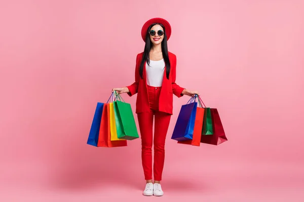 Volledige lengte foto van jong meisje gelukkig positieve glimlach hold tassen winkelen verkoop geïsoleerd over roze kleur achtergrond — Stockfoto