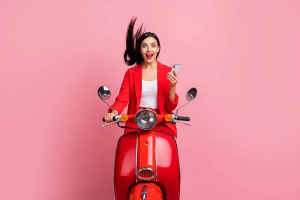 Foto van jong opgewonden meisje blij positief glimlach verbaasd verrast bladeren mobiele telefoon rit fiets geïsoleerd over roze kleur achtergrond — Stockfoto