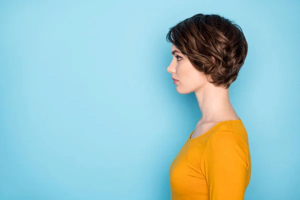 Güzel, esmer bir kadının profil portresi boş görünüyor. Sarı gömlekli, parlak mavi arka planda. — Stok fotoğraf