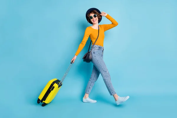 Full Size Profilfoto von optimistischen Brünette Kurzhaarfrisur Dame gehen mit Tasche tragen Hemd Jeans Turnschuhe isoliert auf blauem Hintergrund — Stockfoto