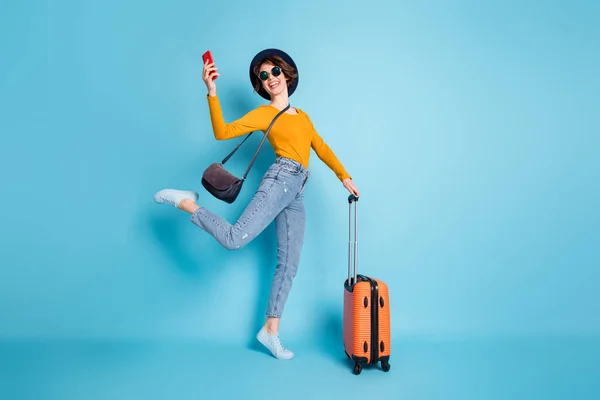Pełna długość ciała rozmiar zdjęcia dziewczyna utrzymanie telefonu komórkowego w terminalu lotniska gotowy do podróży z bagażem izolowane żywy niebieski kolor tła — Zdjęcie stockowe