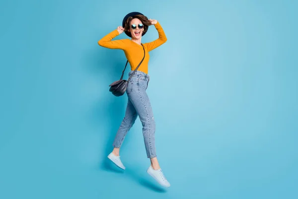 Teljes hosszúságú test mérete fotó lány jumping magas visel napszemüveg kalap nevetés boldog vidám elszigetelt fényes kék háttér — Stock Fotó