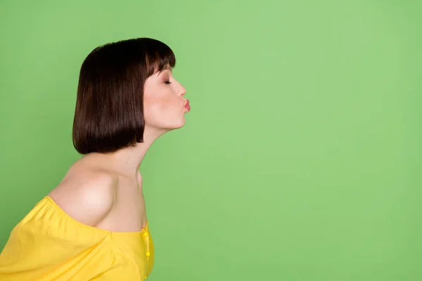 Adatlap side photo of cheerful flirty young charming woman send air kiss empty space isolated on green color background — Stock Fotó