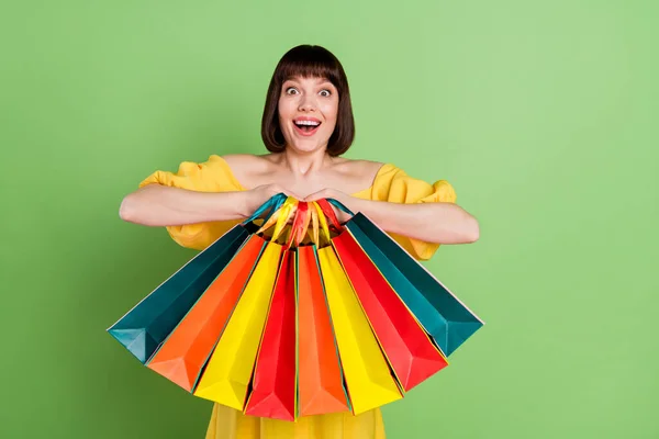 Φωτογραφία από γοητευτικό νεαρή γυναίκα κρατήστε τα χέρια τσάντες ψώνια ενθουσιασμένος πώληση απομονωμένη σε πράσινο χρώμα φόντο — Φωτογραφία Αρχείου