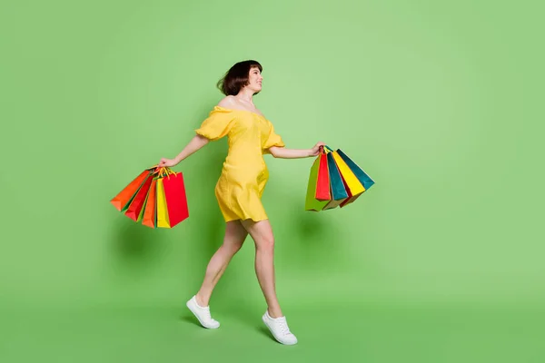 Full size profil boczne zdjęcie szczęśliwej młodej kobiety chodzić puste miejsce torby trzymać izolowane na zielonym tle kolor — Zdjęcie stockowe