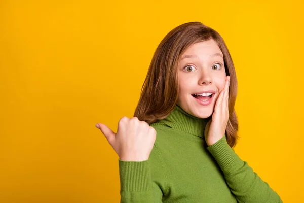 Foto retrato chica joven señalando el pulgar espacio en blanco sorprendido tocando mejilla aislado color verde brillante fondo — Foto de Stock