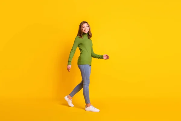 Pleine longueur corps taille photo fille marche vers l'avant dans des vêtements décontractés souriant isolé couleur jaune vif arrière-plan — Photo