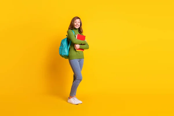 Tamanho total do corpo foto menina mantendo pilha livro vestindo mochila sorrindo isolado vívido cor amarela fundo — Fotografia de Stock