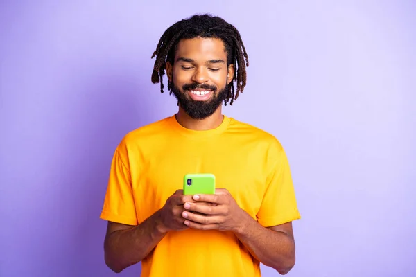Photo optimiste beau brunet homme look téléphone porter t-shirt jaune isolé sur fond de couleur pourpre — Photo