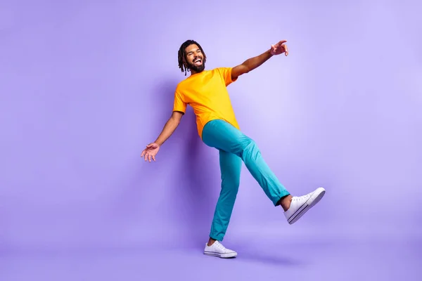 Foto em tamanho completo de bom otimista morena penteado cara dança desgaste laranja t-shirt calças isoladas no fundo cor lilás — Fotografia de Stock