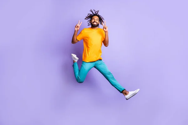 Foto em tamanho completo de agradável otimista morena cara salto mostrar v-sign desgaste t-shirt calças isoladas no fundo cor lilás — Fotografia de Stock