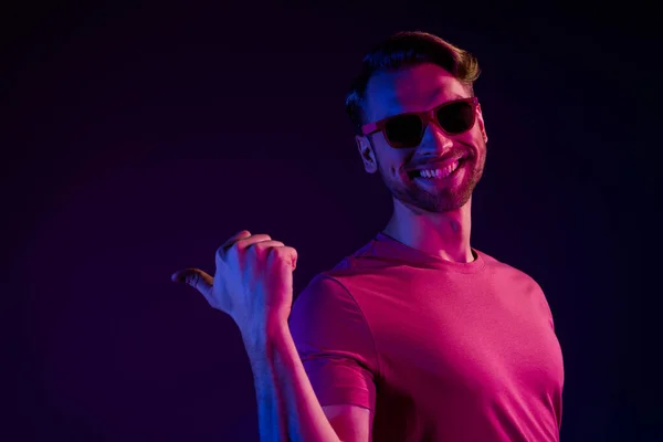 Retrato de chico alegre atractivo demostrando espacio de copia nuevo anuncio novedad aislado sobre fondo de color violeta de neón oscuro — Foto de Stock